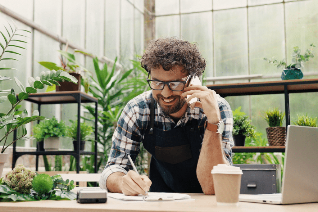 A man smiling while talking on the phone at work
